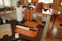 Image showing two large knives on wooden cutting boards, wooden knife blocks, and a small wooden box on a kitchen counter.