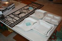 Metal pot rack on table with five white ceramic serving pieces around it