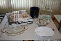 Wide shot of all items including boxed serving tray, blue crock, large glass jar, white Pyrex dish, and glass bowls on metal stands arranged on table