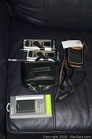 PNY PowerPack T6600, two Storm Tracker weather radios, Canon SureShot camera with case and lens on a dark surface