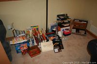 Books arranged on floor including cookbooks, computer, Star Trek, and accounting books alongside office supplies and a briefcase.