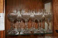 Photo showing 6 Crystal D'Arque wine glasses, clear crystal with cut pattern on bowl, on glass shelf.
