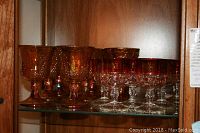 Photo of 8 carnival water glasses and 8 Indiana cordials arranged on a glass shelf.