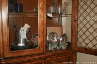 Cabinet shelf displaying the large serving pitcher on a bowl base, oval and round trays, smaller bowls, and creamer.