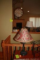Table lamp with floral fabric lampshade placed on wooden railing.