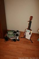 Yamaha Drumpro electronic drum set and wooden ukulele with instruction book on the floor.