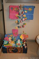 Fish themed towels, wooden fish mobile, toothbrush holder, cup, fish clock, hooks, Kleenex dispenser all arranged on floor and hanging from a rack
