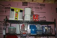 Shelf holding Oster ice cream maker, various plastic storage containers, two glass pitchers, and other kitchen items.