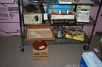 Shelves with various boxed and loose kitchen items, including pans, chopper, popcorn popper, small pot and bowl