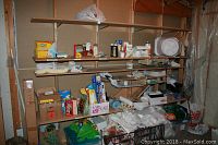 Wide shot of shelving unit containing various home maintenance and cleaning products, paper towels, plastic containers, bags, and boxes.
