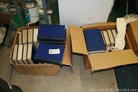 Box of 47 bound blue hardcover National Geographic volumes, stacked and partially open showing intact spines and covers.