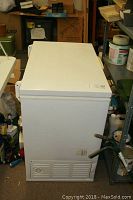 Closed white General Electric chest freezer in a storage space, showing full size and general condition.