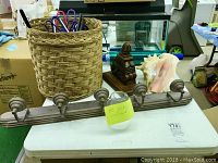 Photo showing entire lot laid out on a white table, including light bar fixture with glass globes, large conch shell, woven basket with hangers, and wooden wall decor piece.