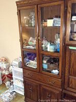 Wooden wall unit from the front showing glass doors, central drawer, and bottom double-door cabinet.