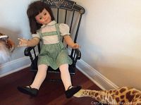 Doll sitting in Hitchcock style rocking chair showing full view of doll and chair