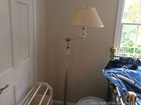 Floor lamp with clear stand and cream pleated shade in a room corner