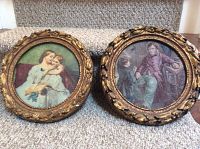 Two round hand-painted Artini engravings with gold leaf frames sitting on carpeted stairs, showing full view and size reference
