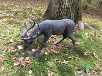 Photo of larger and smaller resin buck lawn ornaments outdoors on grass with leaves around, showing overall condition and scale.