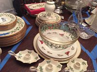 Stacks of Lenox Holiday porcelain plates, glass bowl and candlestick holders on table