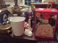 Room view showing Lenox snowman in box, ceramic vase, brown pot, bride and groom figurines, angels, clear box, and other assorted items