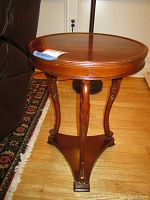 Front view of the ornate round wooden side table showing the carved legs and structure