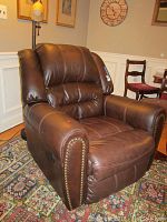 Another angled view from front side showing the chair's thick cushioned back, armrests, and a tag visible on the side with serial number.