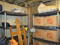 Full view of two black plastic shelving units in basement closet, with boxes and items stored on and around them.