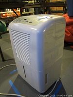 Front angle view of white GE dehumidifier showing side air vents and power cord.