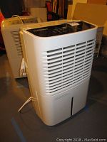 Front angle view of white Prime Aire dehumidifier showing ventilation grill and power cord on floor.