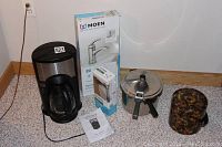 Full lot showing all items: coffee maker, pressure cooker, ice bucket, boxed Moen faucet and toilet paper holder.