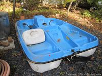 Top and front side view of the paddle boat showing the blue seating area and paddle pedals with white hull beneath.