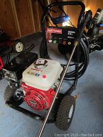 Front-left angle view showing engine, hose reel, wand storage