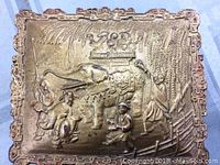 Top view showing embossed elephant with crown and surrounding human figures in traditional dress, intricate embossed foliage background and decorative border