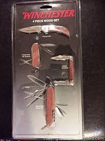 Four knives/tools in sealed packaging marked Winchester 4 Piece Wood Set.