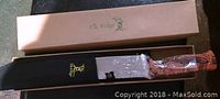 Knife in box showing knife handle, sheath, and box inside.