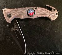 Photo of American Patriot folding pocket knife with handle and partially open black blade showing emblem on handle.
