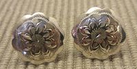 Front view of the pair of sterling silver earrings showing floral engraved design and scalloped edges.