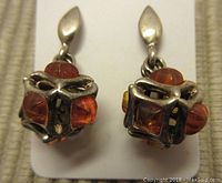 Pair of vintage amber earrings showing front view of one earring mounted on card, showcasing amber cubes and oxidized silver setting.