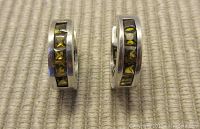 Close-up front view of the pair of sterling silver hoop earrings showing channel set citrine-colored square stones.