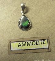 Front view of pear-shaped ammolite pendant in twisted silver frame