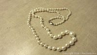 Full view of the single strand pearl necklace with gold filled lobster clasp.