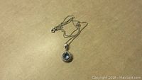 Sterling silver chain with attached blue topaz pendant showing front view with gemstone.