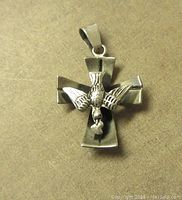 Front view of the sterling silver cross pendant displaying the bird holding a heart detail