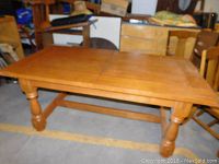Solid wooden farmhouse-style dining table with turned legs and stretchers, viewed from the front side showing the full table length without leaf.