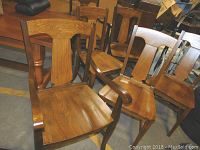 Front view showing 2 arm chairs and 4 side chairs grouped together in storage area with visible curved backrests and armrests on two chairs.