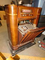 Angled right-front view showing wood cabinet, open lower door revealing phonograph turntable mechanism