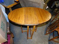 Front view of wooden drop leaf table with both leaves extended in a round shape