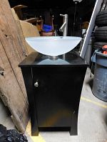 Front black wood vanity cabinet with door closed, glass bowl sink and lever faucet on top