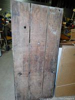 Front view of the wooden barn style door showing large vertical wooden planks, rustic and heavily used condition.