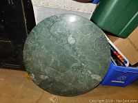 Top-down view of a polished round green marble table top, showing surface pattern and size.